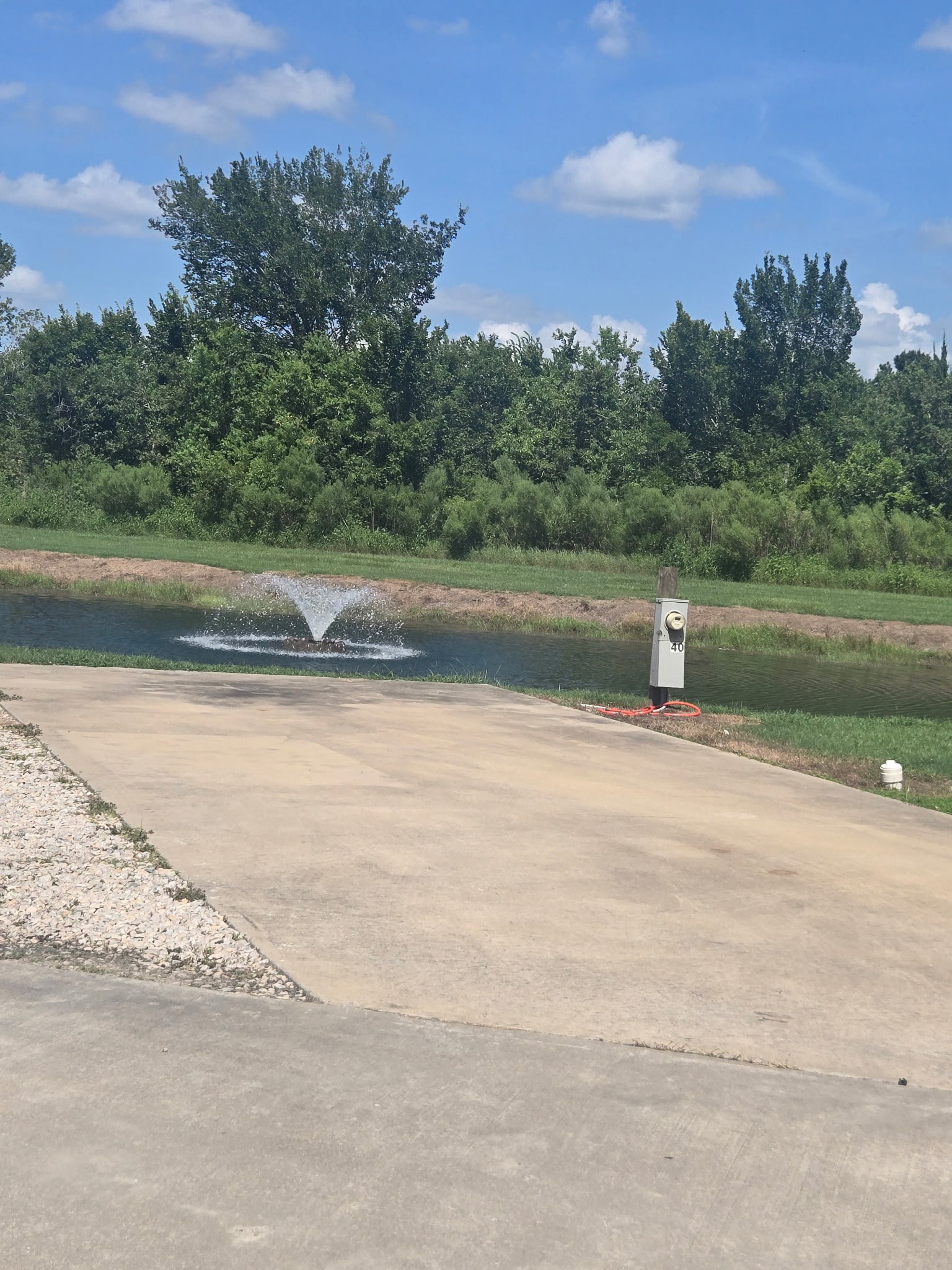 Concrete pad RV site overlooking the stocked fishing pond with fountain