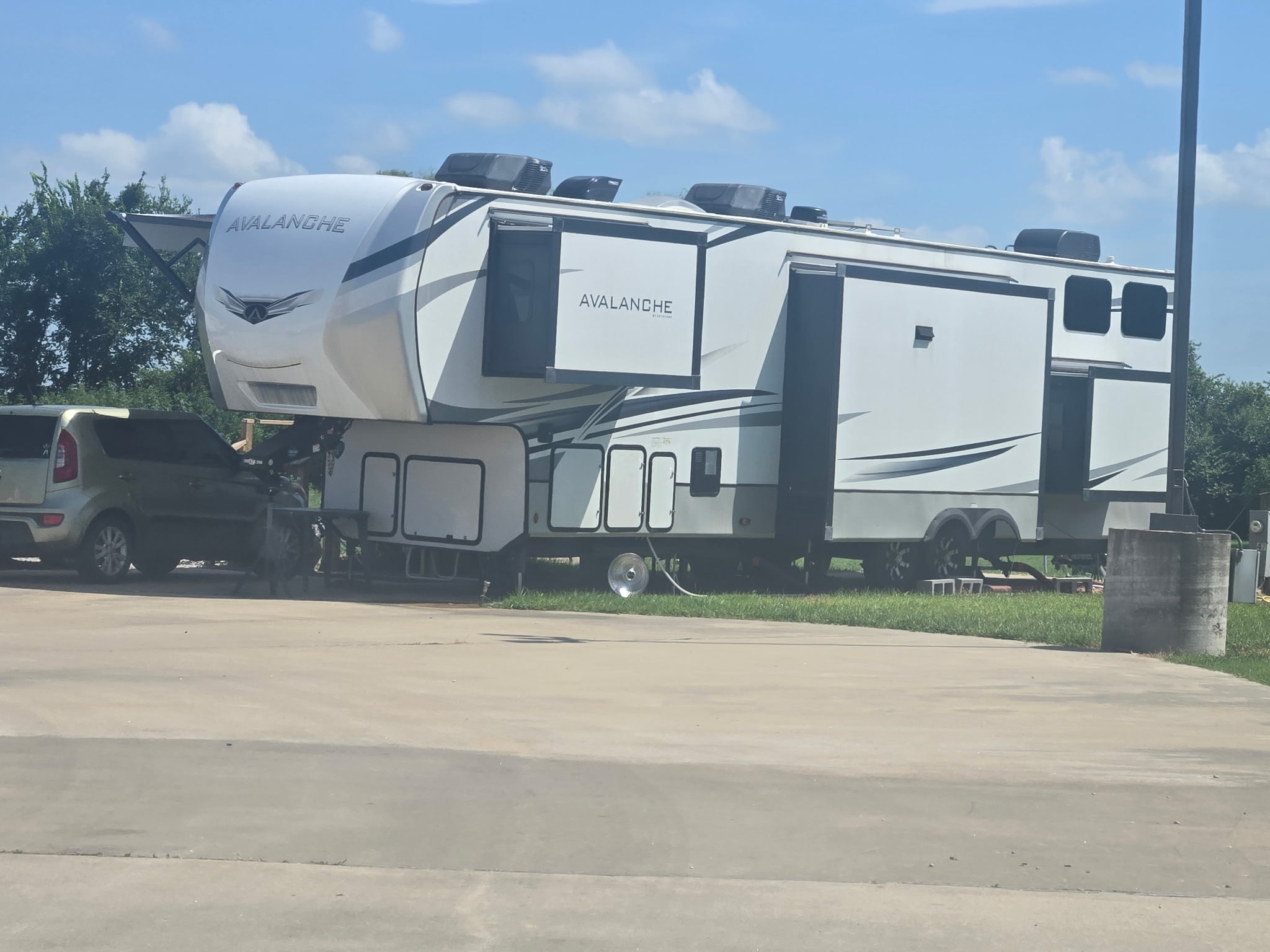 Avalanche fifth-wheel trailer parked on a spacious concrete pad site